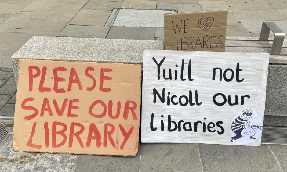 Cardboard signs reading 'please save our libraries', 'Yuill not Nicoll our libraries' and 'we (heart) libraries'