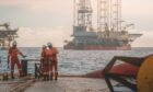 Workers with an offshore oil rig in the distance