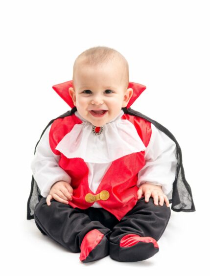 A baby dressed in a Dracula vampire costume
