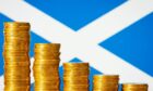 Piles of coins in front of a Scottish Saltire