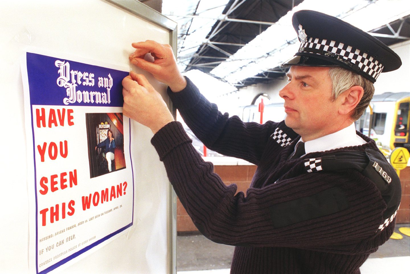 A British Transport Police officer putting up a missing poster for Arlene Fraser
