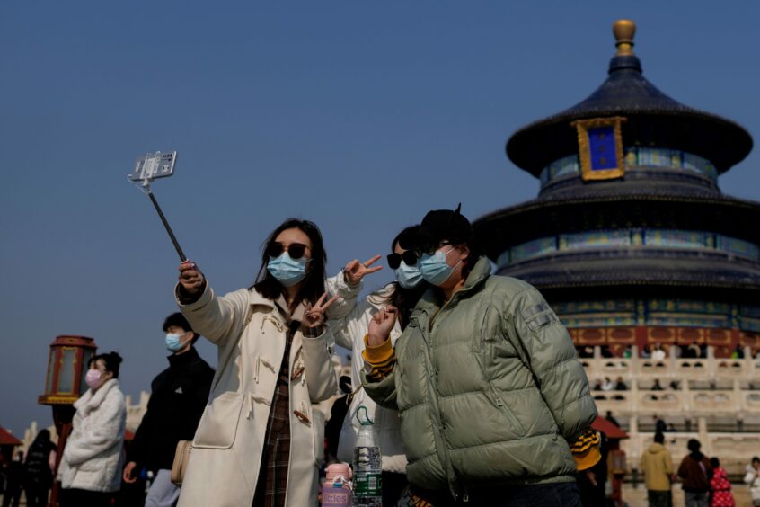 Women wearing face masks take a selfie as they visit the Temple of Heaven park in Beijing.