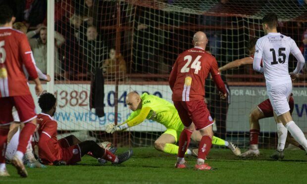 Brora Rangers goalkeeper Logan Ross, in yellow, plunges on the ball to deny Brechin City.