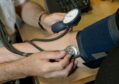 A GP checks a patient's blood pressure.