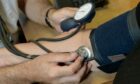 A GP checks a patient's blood pressure.