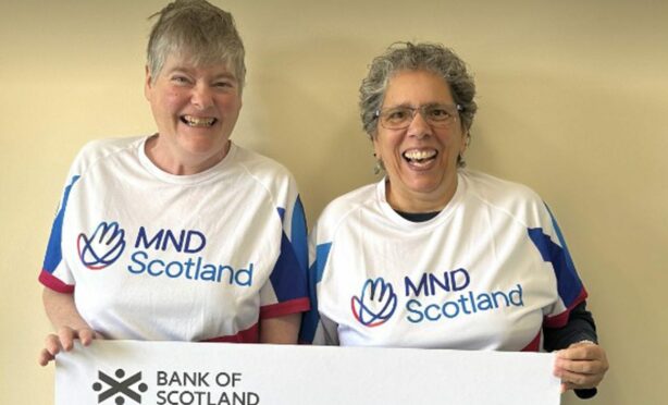 Two smiling women hold a check from a fundraising event.