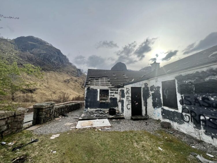Exterior of Jimmy Savile house in Glen Coe, covering in graffiti with curse words blacked out.