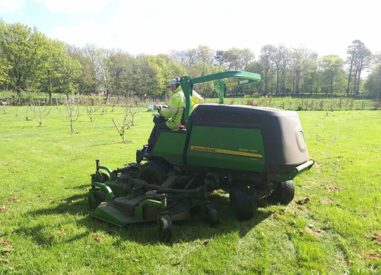 Man on a wide area lawn mower.