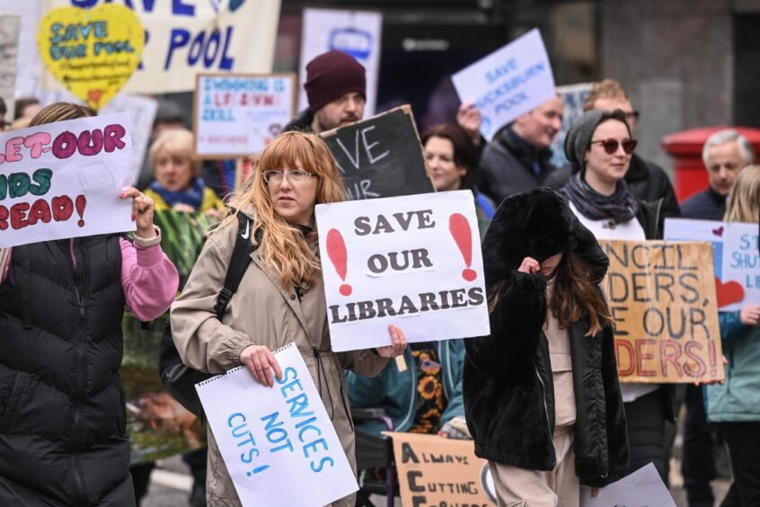Campaigners hold signs that say "Save our libraries" during a May Day march in Aberdeen. 