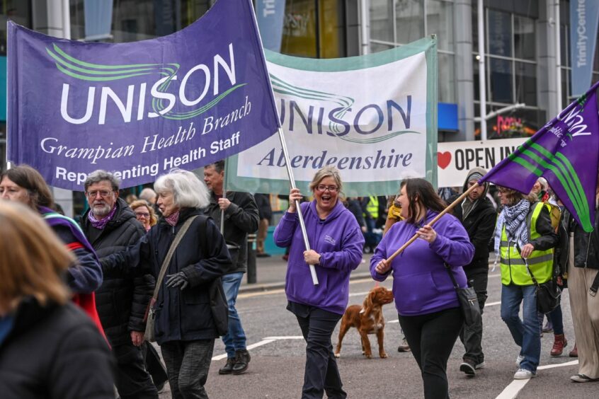 Unison and Unite members march along Union Street holding banners. 