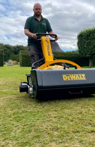 Man using an electric cylinder mower.