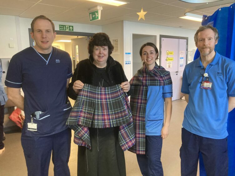 Linda Gorn holding the tartan, with members of the Aberdeen Cardiac Team standing next to her
