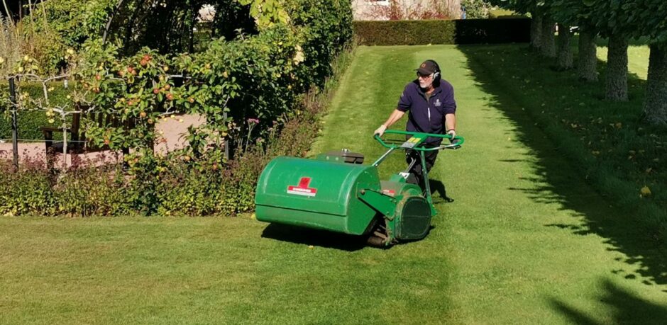 Man using a cylinder mower.