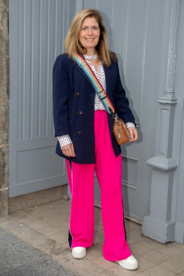Aberdeen woman in bright pink trousers, white polka dot blouse and navy blue blazer.