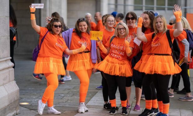 Maggie's Culture Crawl participants breaming in bright orange T-shirts, tutus and legwarmers.