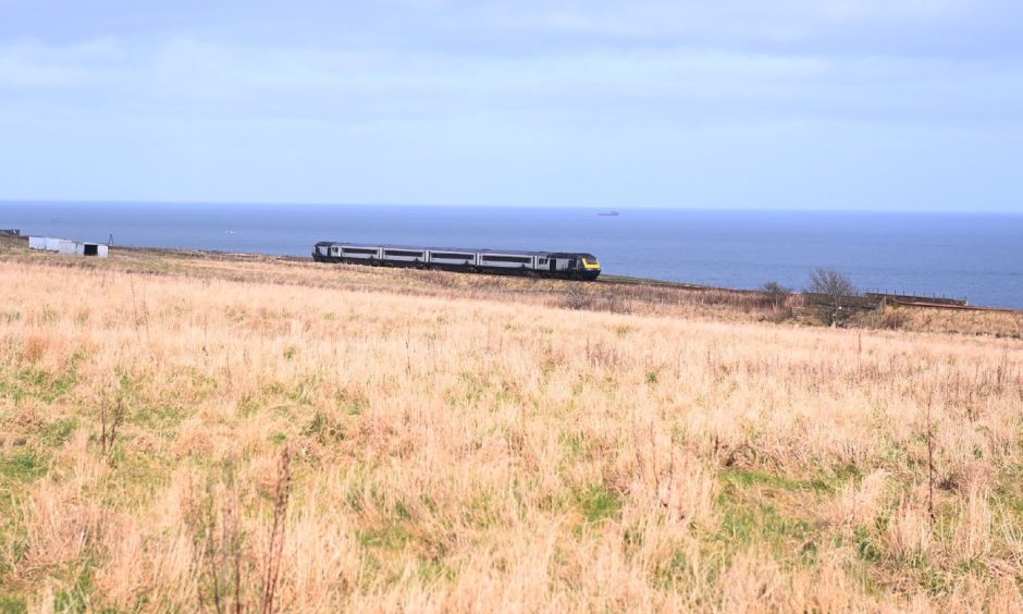 A train passing Cove in Aberdeen, with the North Sea in the background