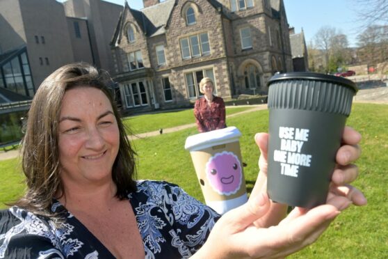 Tara Jaffray, owner of Corner on the Square in Beauly with one of the reusable cups, and Catherine Gee, deputy chief executive of Keep Scotland Beautiful. Image: Sandy McCook/DC Thomson.