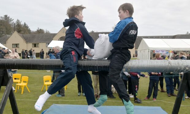 Kids battle it out on the slippery pole representing their school at the Junior Highland Games. Image: Sandy McCook/DC Thomson.