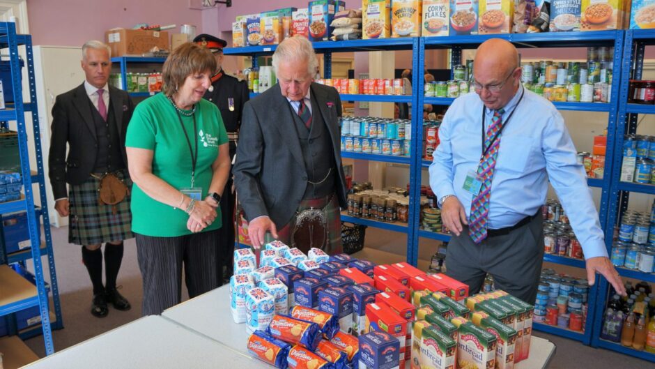 Pat Ramsay and her husband Grant show King Charles some of food donations they've received. 