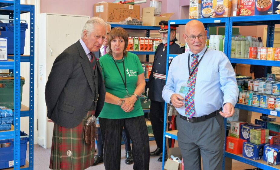 Pat Ramsay and her husband Grant show King Charles some of food donations they've received. 