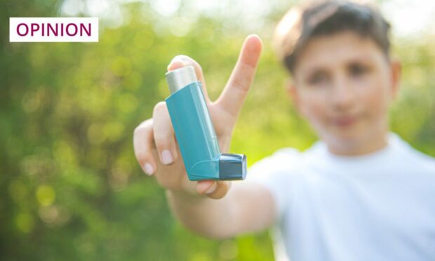 Young boy holding asthma inhaler.