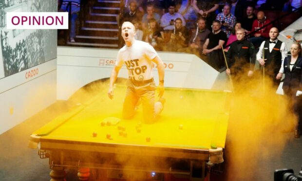 A Just Stop Oil protester jumps on the table and throws orange powder during the World Snooker Championship at the Crucible Theatre in Sheffield (Image: Mike Egerton/PA)