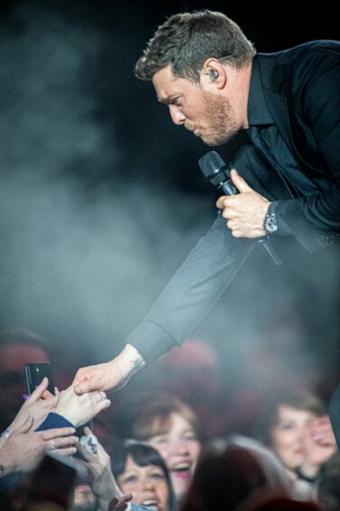 Michael Bublé reaching down to shake a fan's hand while performing at P&J Live in Aberdeen.