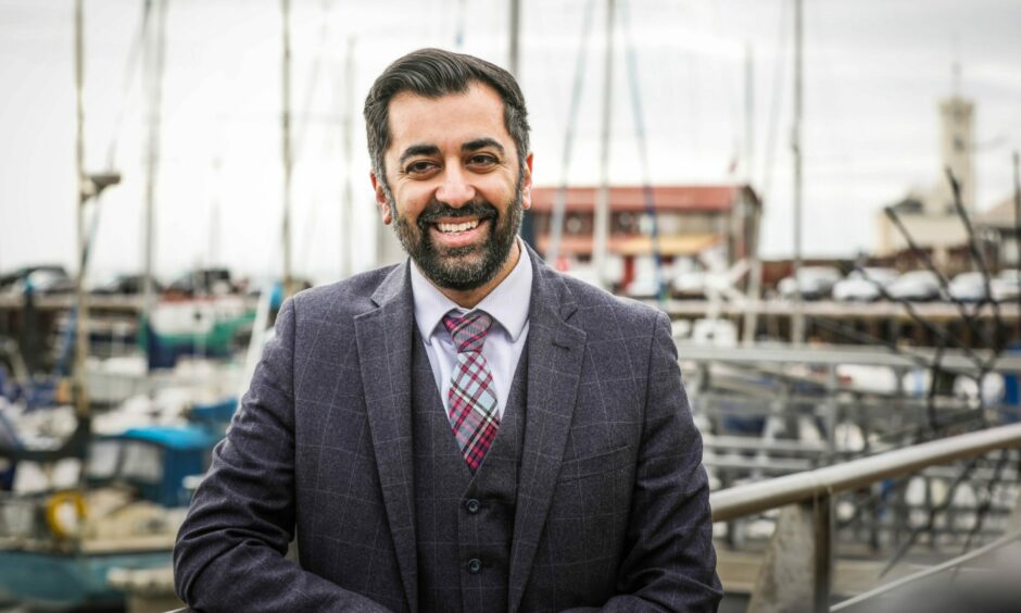Humza Yousaf standing at Arbroath Harbour smiling.