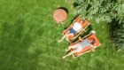 Aerial view of couple sunbathing on loungers in their garden.