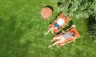 Aerial view of couple sunbathing on loungers in their garden.