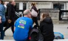 A man sits on a bench with the words 'You'll never sing alone' on his T-shirt near the Eurovision village in Liverpool. Image: Dave Rushen/SOPA Images/Shutterstock.