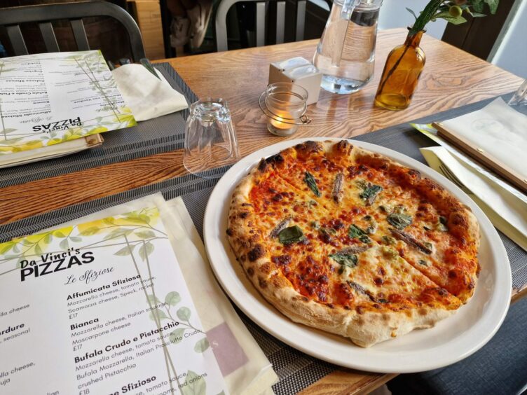 Pizza and menus on a table at Da Vinci Restaurant.