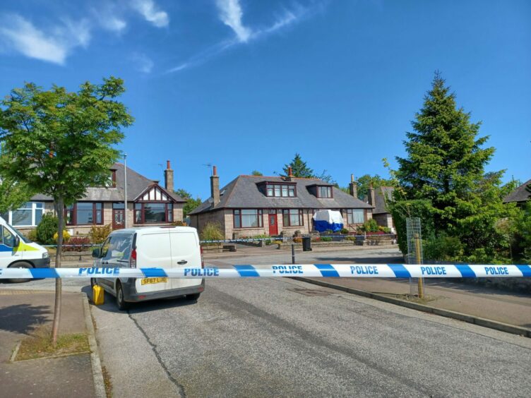 A photo of Rosehill Crescent cordoned off with police tape in the foreground and the broken window covered up at the property. 