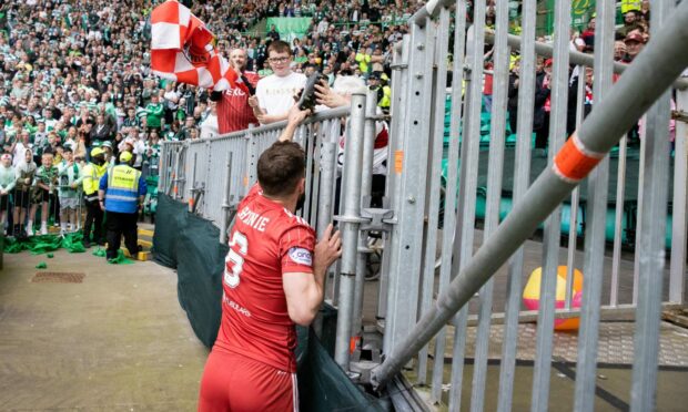 Aberdeen's Graeme Shinnie hands his boots to a Dons fan after the game against Celtic. Image: SNS.