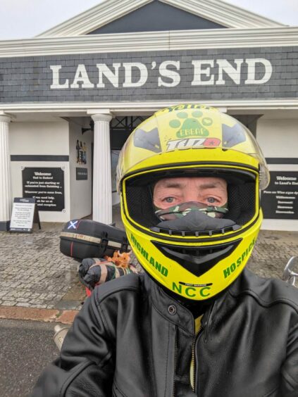 George Maciver wears his bike helmet in front of Land's End 