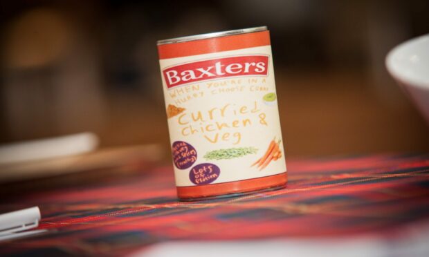Can with hand-drawn curried chicken and vegetable soup label on a tartan blanket.