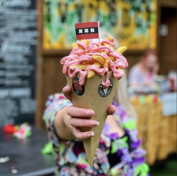 Hand holding fries with pink mayo.