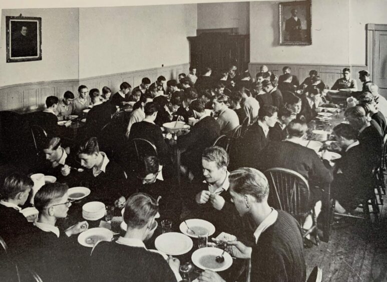 1960s photo of pupils dining in Gordonstoun beneath a portrait of Prince Philip.
