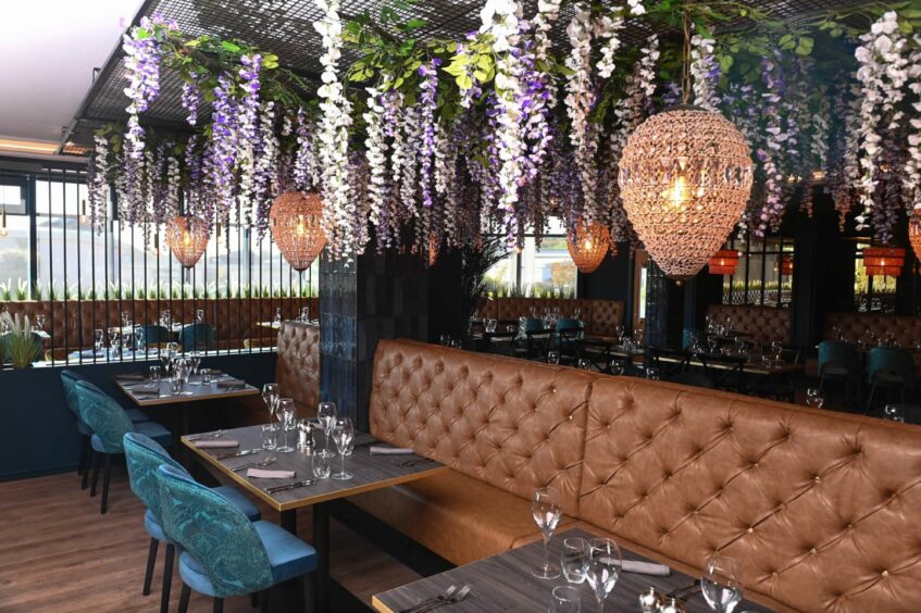Another view of the restaurants interiors featuring stylish chandeliers and flowers hanging from the ceiling.