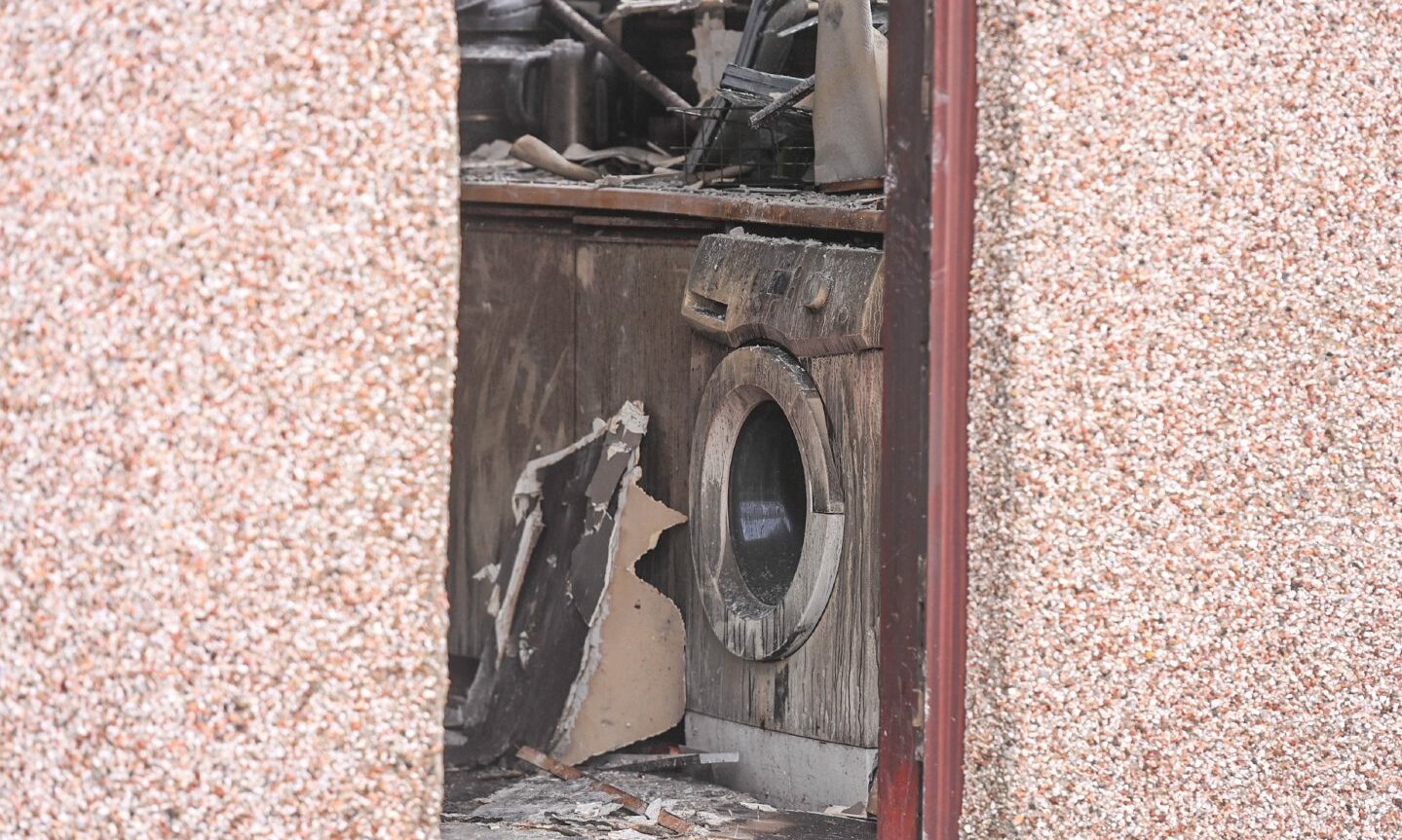 Looking through an open door at a fire-damaged washing machine. 