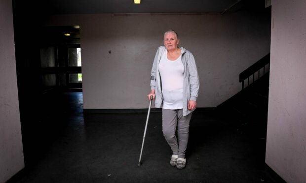 Heather Petrie stands in the dark stairwell while leaning on one crutch.