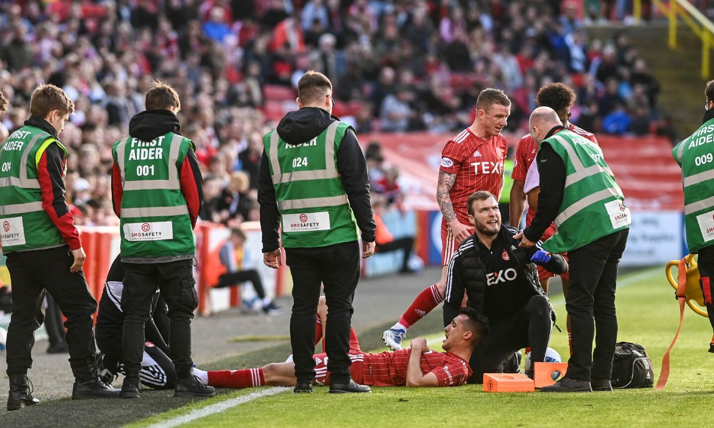 First aiders and other Aberdeen players gathered around Bojan Miovski lying at t side of the pitch after an injury