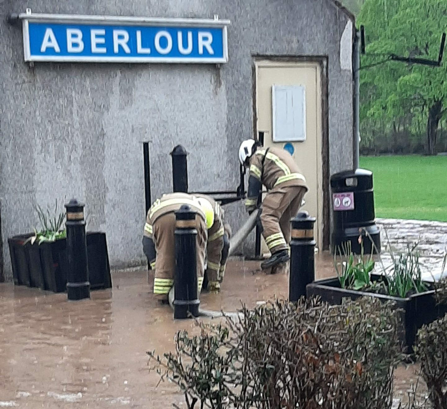 Two firemen trying to pump out water next to the old station tearoom in Aberlour. 