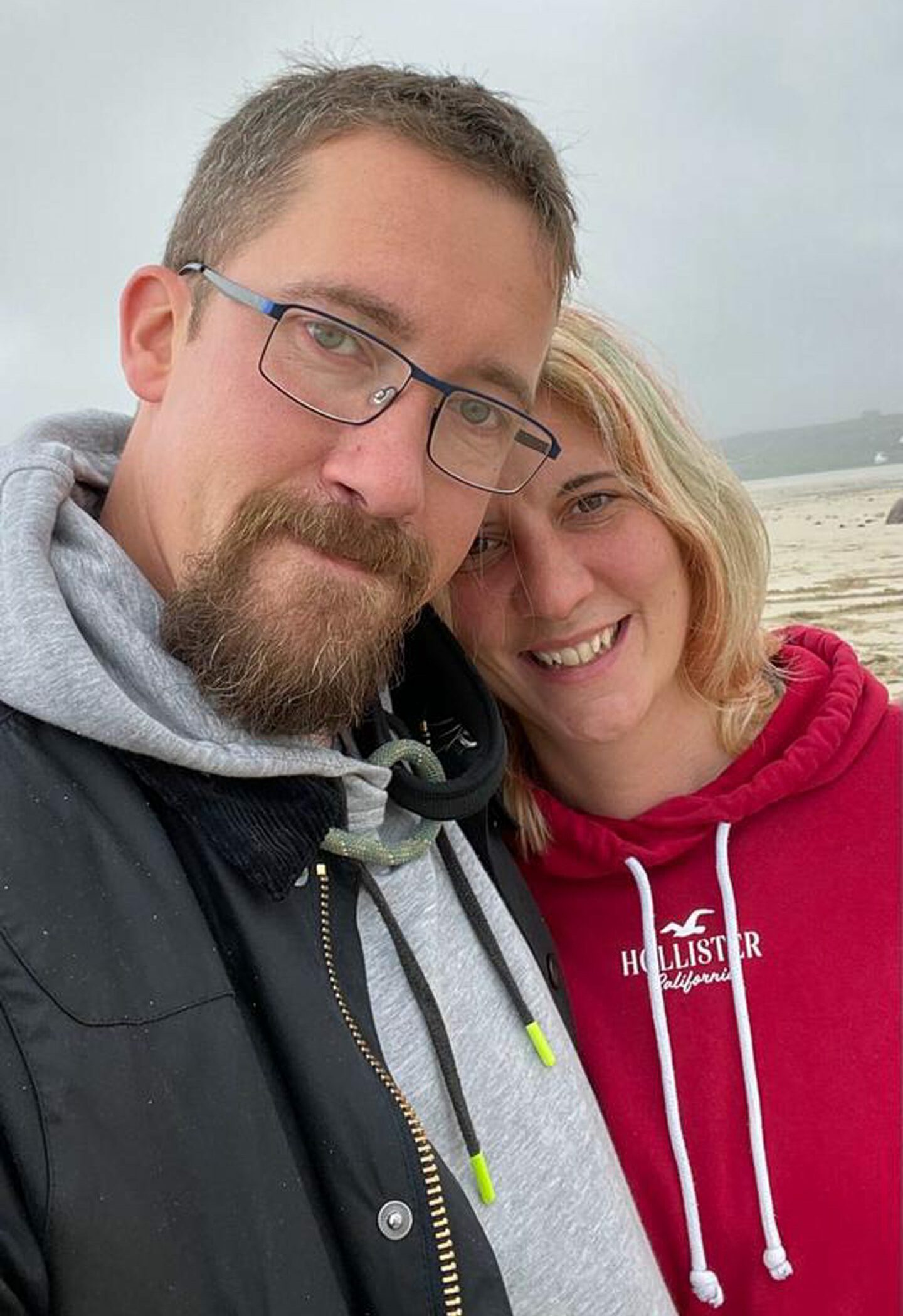 Mike Emeny and Beth Oxley embrace while on a beach. 