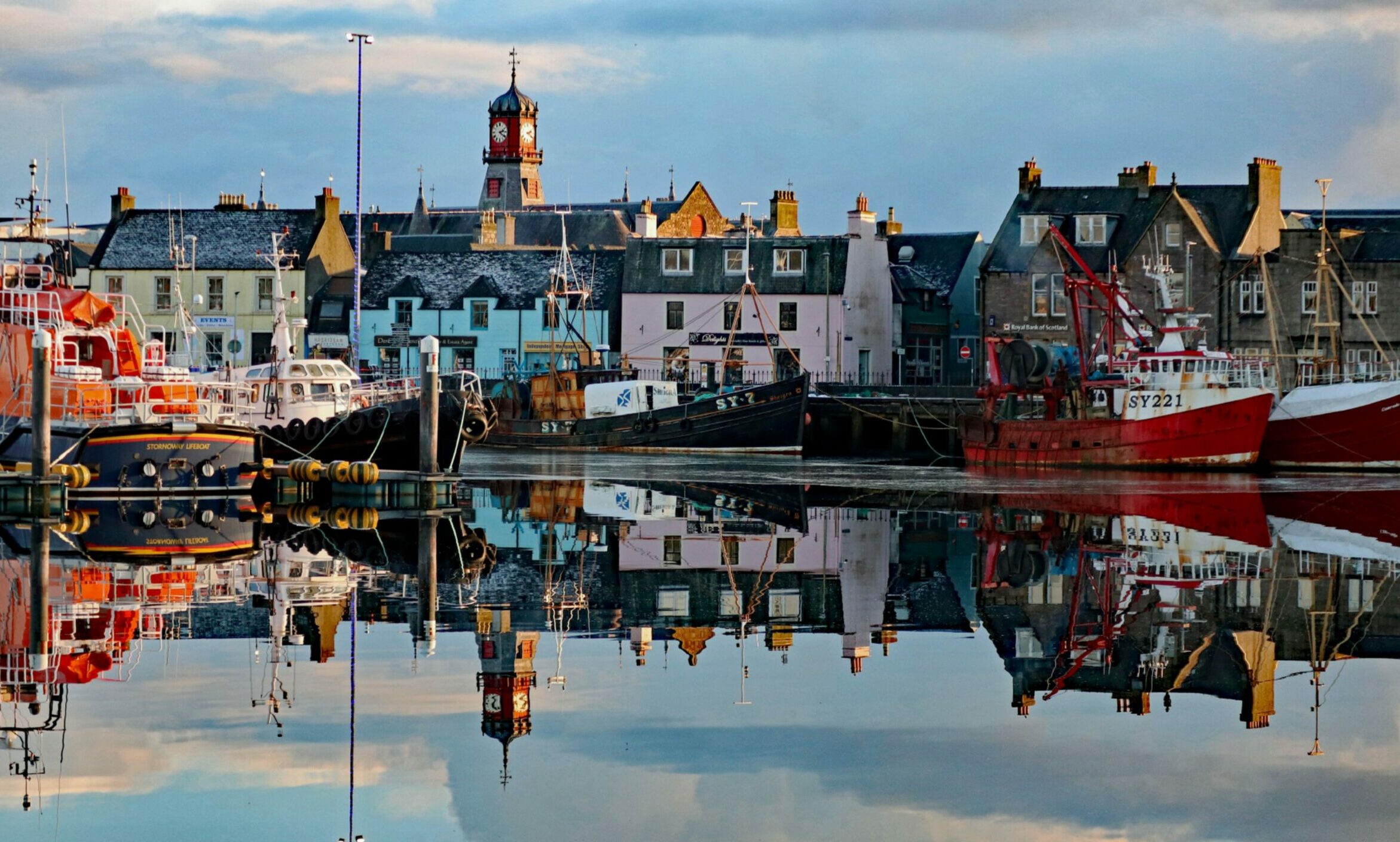 Stornoway on the Isle of Lewis. plenty of colourful houses, with fishing boats in the water in the foreground. This is the main town in the Western Isles.