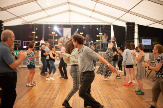 A group of festival-goers dancing in a hall at Speyfest.