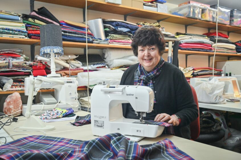 Linda Gorn, who designed Hearts of Grampian tartan for Aberdeen cardiac team, sat behind a sewing machine with her tartan on the table next to her.