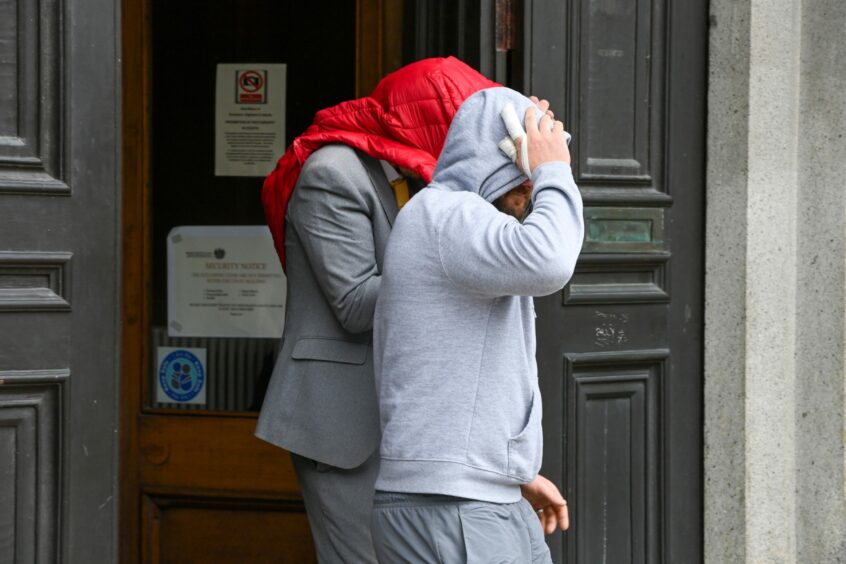 David Will exiting court with a red jacket covering his head.
