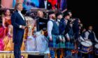 Andre Rieu on stage at the P&J Live with members of the Deeside Caledonia Pipe Band who are all wearing a green tartan. Behind them is members of Rieu's orchestra.