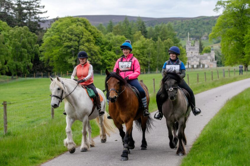 A trio of riders with Balmoral Castle in the background.